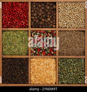 Assorted fresh colorful spices and condiments in a wooden organizer box, elevated top view, directly above Stock Photo