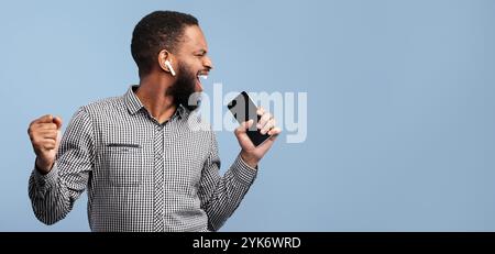 Happy afro man singing using smartphone as mic Stock Photo