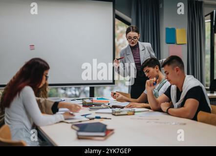 Young students collaborating with teacher in modern classroom setting Stock Photo
