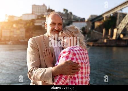 Couple embracing by the river in a picturesque city during sunset Stock Photo