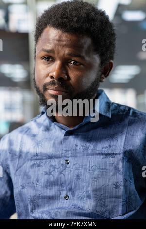 System administrator doing software quality assurance, writing source code on computer. African american man at work in office inspecting coding on PC, looking to fix potential issues Stock Photo