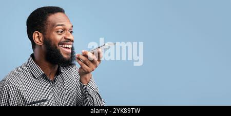 Happy afro man using voice assistant on smartphone Stock Photo
