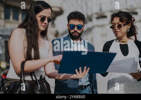A group of diverse professionals engaging in a collaborative outdoor business meeting, reviewing documents together. Stock Photo