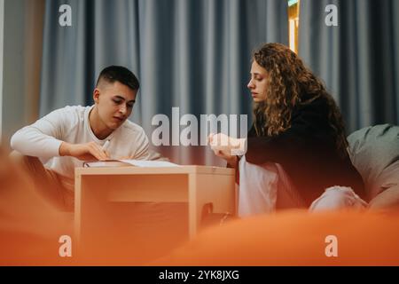 Two students collaborating on a school project at a modern educational setting, showcasing teamwork and focus as they sit together and engage with Stock Photo
