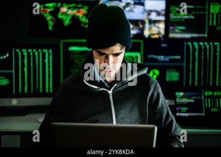 Young hacker man breaking into corporate servers from his home office Stock Photo