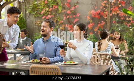 Waiter takes an order from a couple in love who decided to meet in an open air restaurant Stock Photo