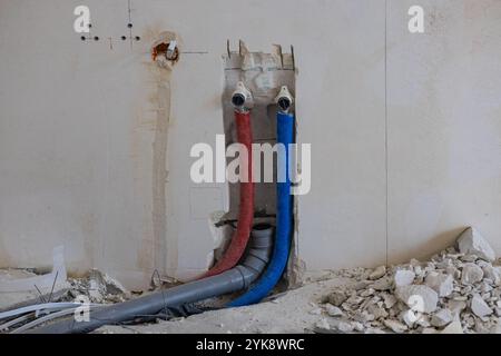 Installation of plumbing and electrical systems in a house under construction with wall fittings and scattered construction debris. Stock Photo