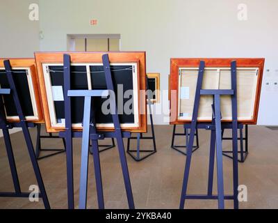 Wooden easels at a museum art exhibit seen from behind; rear view of paintings in wood frames. Stock Photo