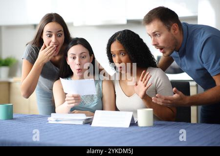 Amazed interracial friends checking receipt in the kitchen at home Stock Photo