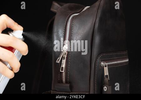 Applying the spray to a leather backpack, accessories care Stock Photo