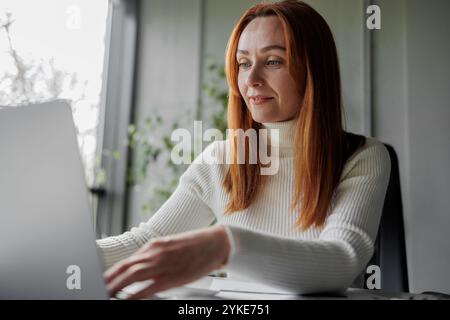 Woman Working on Laptop in Bright Office Stock Photo