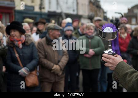 Farming community UK, a silver cup and rosette is being presented at the annual Christmas Fatstock Market held in temporary penning in a town market square. Livestock, auctioneer Alastair Sneddon presenting a silver cup to an exhibitor.  Uppingham, Rutland, England 24th November 2021.HOMER SYKES Stock Photo