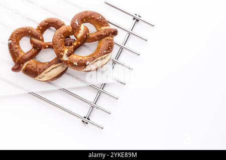 Freshly baked bread pretzels on a baking cooling metal rack over white background Stock Photo