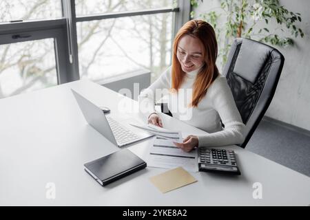 Businesswoman Analyzing Financial Documents in Modern Office Stock Photo