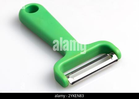 Green vegetable peeler with stainless steel blade isolated on white background. Kitchen utensils and equipment Stock Photo