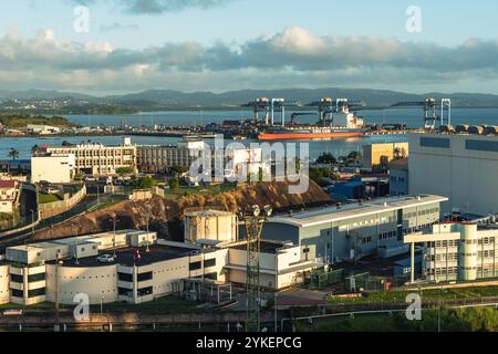 Fort-de-France, Martinique - January 3, 2018: Loading of cargo merchant ship in picturesque port against sunset sky. Stock Photo