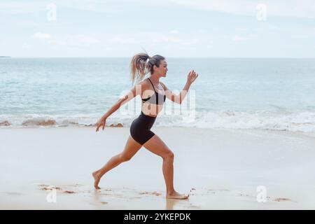 Woman doing jump squats on beach Stock Photo