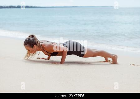 Woman doing push up on white sand beach Stock Photo