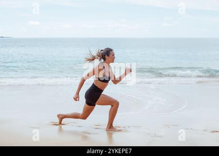 Woman doing jump squats on the beach Stock Photo