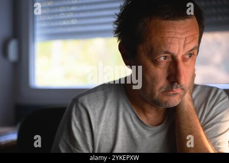 Mature man focused on computer screen in home office, selective focus Stock Photo