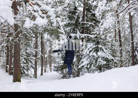 Rear view young woman running towards snowy trees in snowfall Stock Photo