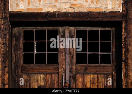 Old wooden door with broken glass windows of an abandoned industrial warehouse as background Stock Photo