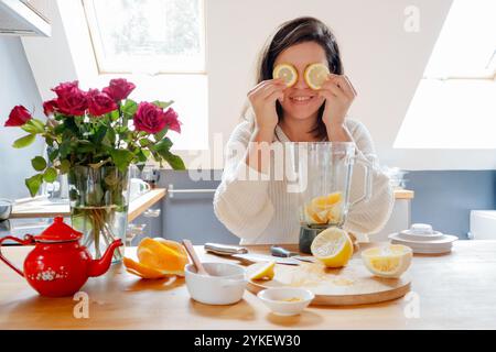 A woman put lemons on her eyes - fun in the kitchen Stock Photo