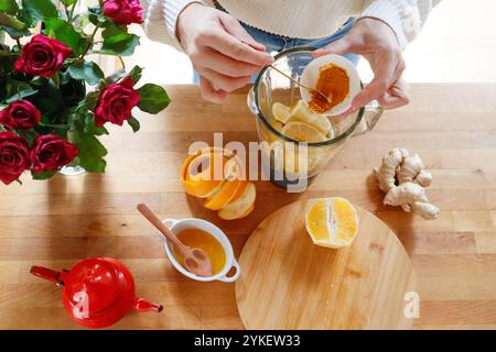 Top view - hands add turmeric to a blender with citrus fruits Stock Photo