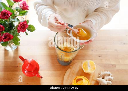 Top view - hands add honey to blender with citrus fruits for tea Stock Photo
