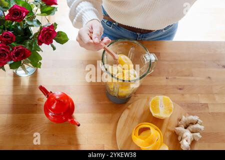 Hands add honey to blender with orange and ginger for tea Stock Photo