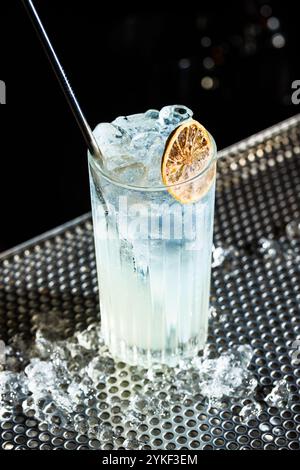 A refreshing gin fizz cocktail served in a tall glass, garnished with a slice of lime and filled with ice cubes Stock Photo