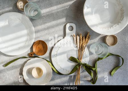 A rustic table set features wheat-themed ceramics with a natural, minimalist design Includes plates, bowls, and glasses, accented by wheat stalks and Stock Photo