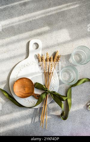 A stylish table setting features a rustic wheat theme A ceramic plate, wooden scoop, and green ribbon accentuate the natural elements, creating an ele Stock Photo