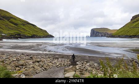 Young man exploring Tjornuvik black sand beach on Eysturoy in the north Atlantic Faroes Solo travel, touristic excursions and explore nature trips Stock Photo