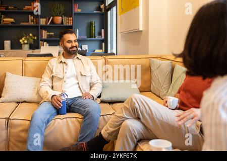 Casual meeting in a cozy coworking space, with individuals sitting on a comfortable couch and engaging in conversation Stock Photo