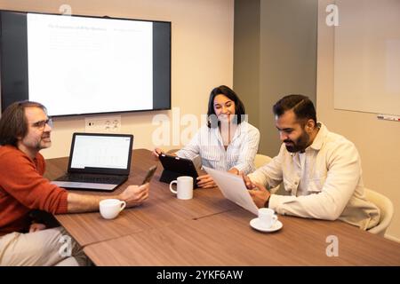 Group of professionals engaged in a team meeting in a modern coworking space, using laptops and tablets The environment fosters creativity and collabo Stock Photo