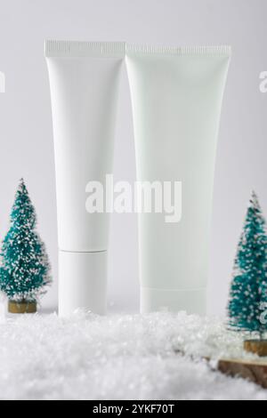 Cosmetics tubes on a fake snowy surface with mini Christmas trees, capturing the essence of festive gifts and winter beauty products. Stock Photo