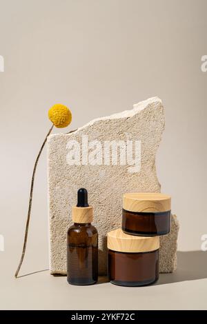 High-end skincare products presented on textured stone podiums, with a yellow craspedia flower adding a touch of color. Stock Photo