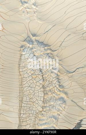 A detailed image showcasing an array of dried mud cracks creating a complex, natural pattern on a beige colored surface. Stock Photo