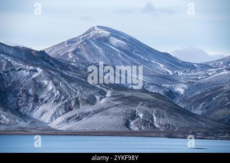 Captivating view of the Icelandic Highlands, featuring a snow-dusted mountain landscape beside a serene lake. The muted colors of the scene evoke a se Stock Photo