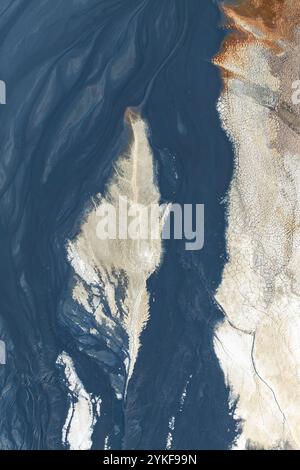 An abstract aerial composition from Riotinto, featuring swirling textures in dark blue, beige, and rust tones The intricate natural patterns evoke a s Stock Photo