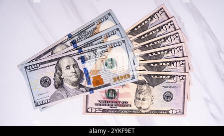 A close-up shot of various US dollar bills, including 100 and 50 denominations, arranged on a light marble surface Ideal for themes of finance, invest Stock Photo