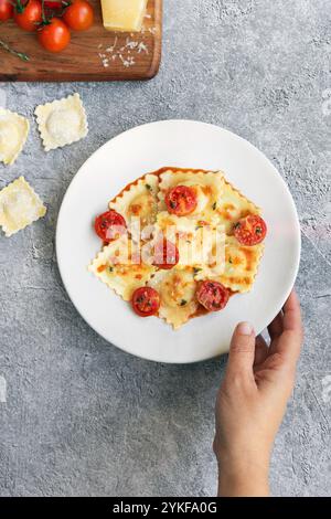 A delicious serving of ravioli stuffed with goat cheese and caramelized onions, topped with a rich tomato sauce and garnished with candied cherry toma Stock Photo