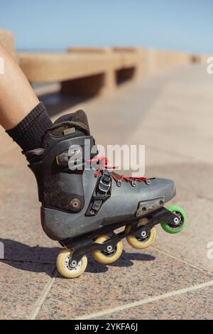Cropped unrecognizable young person rollerblading outdoors, showcasing a close-up of worn inline skates on a sunny day. Stock Photo