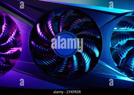 Close-up of high-performance graphics card with cooling fans illuminated by neon lighting. Modern video card for gaming and advanced computing Stock Photo