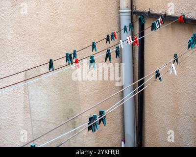Multi color of clothespins on clothes line without clothes on concrete wall background at the space of old house. Stock Photo