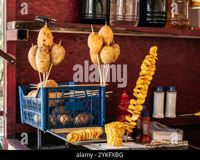 Fried spiral spring potato chips on stick with corn cup, Georgian street food at Georgia, preparing in the local shop for sale to traveller, tourist c Stock Photo