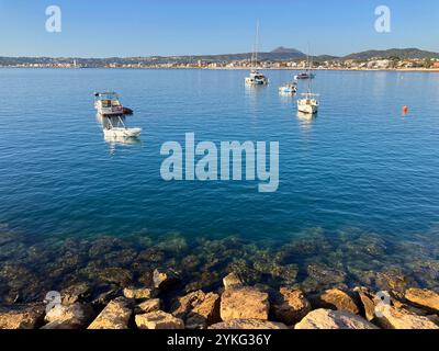 view across bay from breakwater to boats at anchor, seafront and Mediterranean coastline Stock Photo