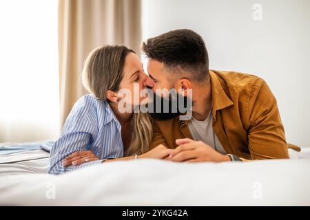 Young happy couple is lying on bed and kissing. Couple in love. Stock Photo