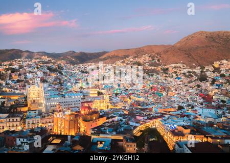 The illuminated cityscape of Guanajuato, Mexico at blue hour highlights colorful hillside homes and iconic landmarks under a serene twilight sky. Stock Photo